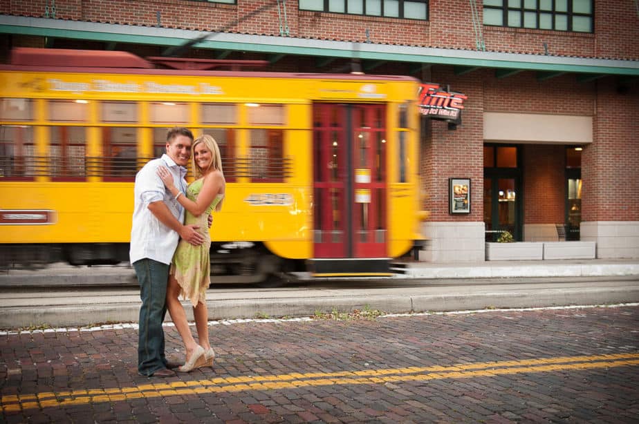 Engaged couple photographed in front of a passing yellow streetcar